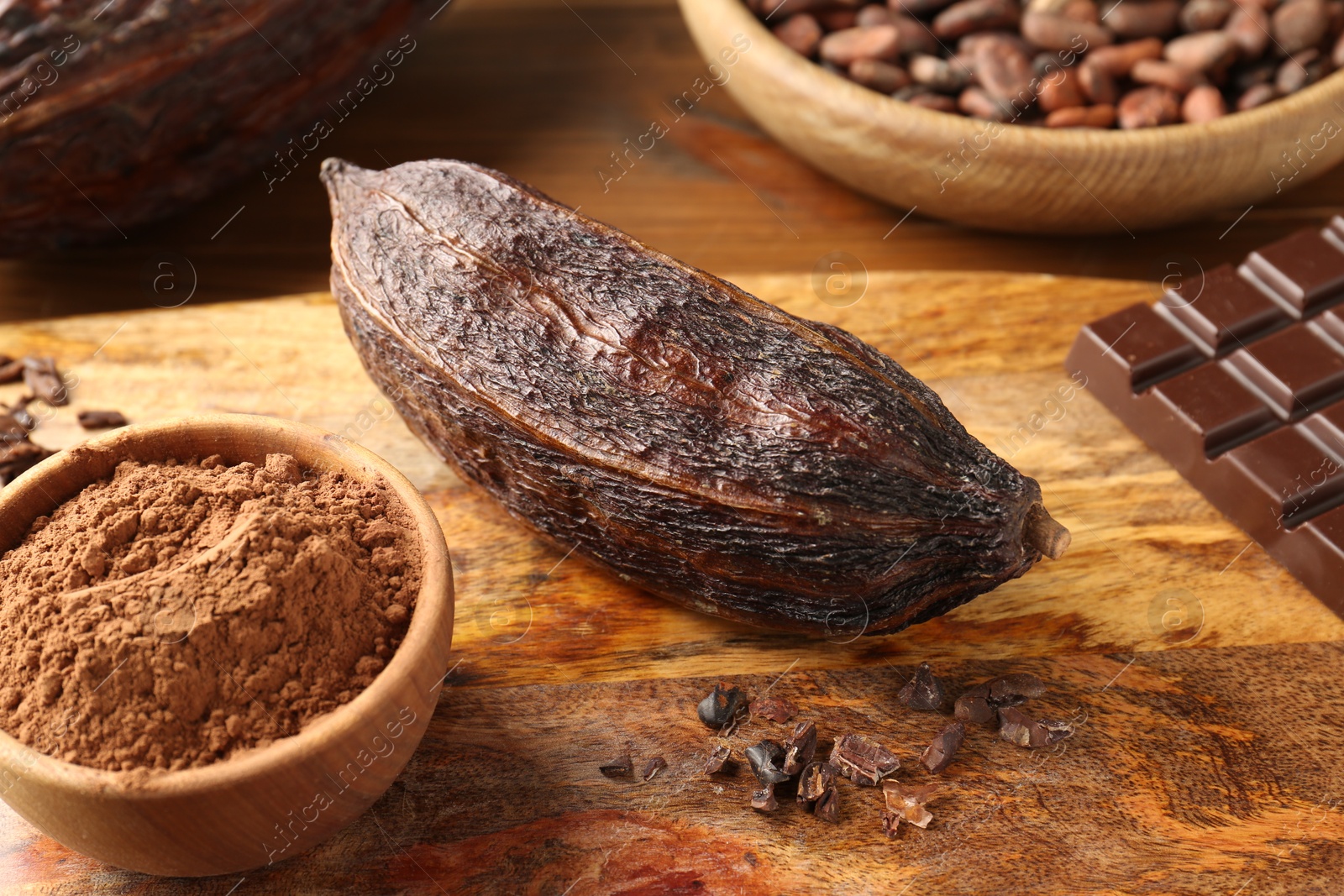 Photo of Cocoa pod, beans, powder and chocolate on wooden table, closeup