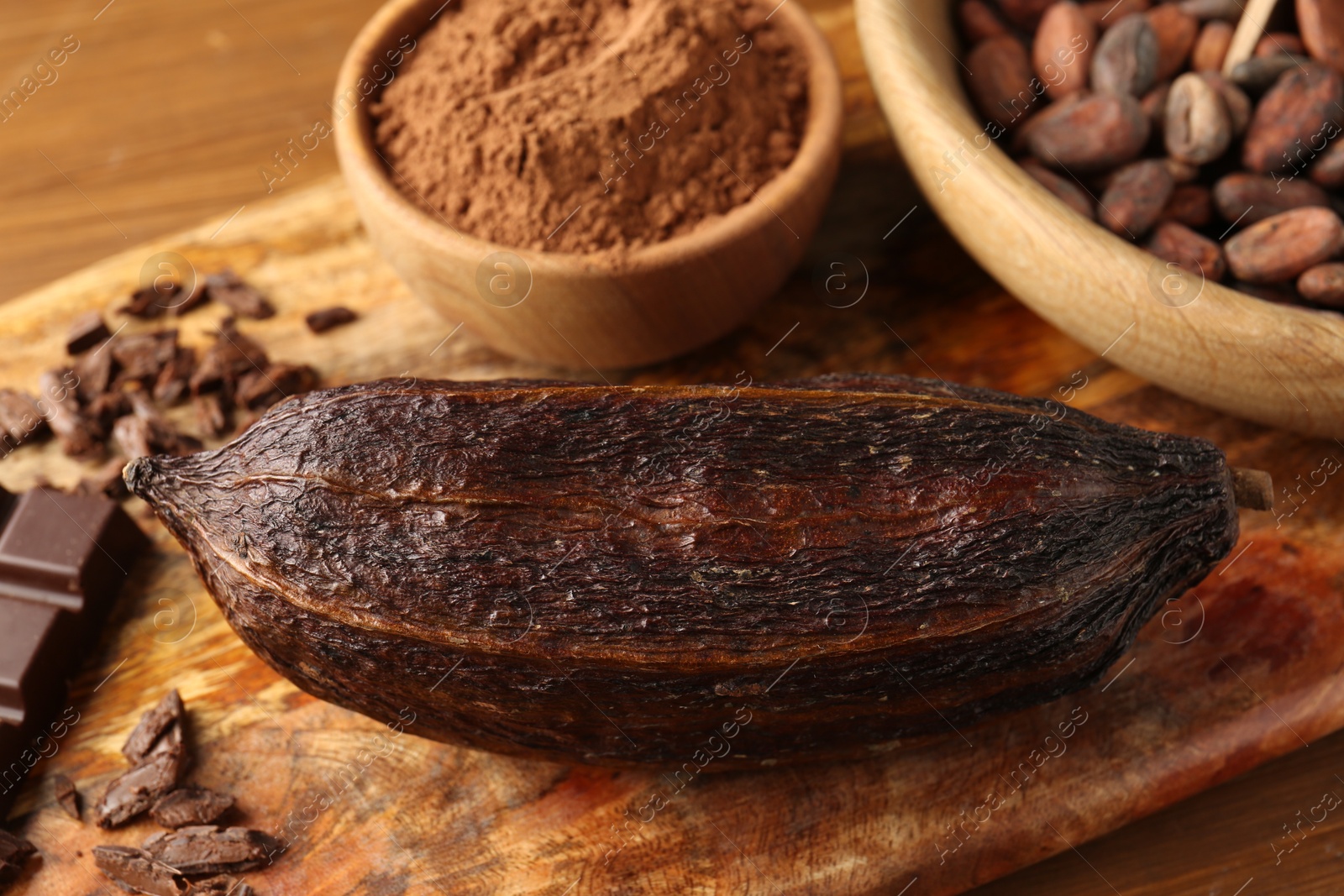 Photo of Cocoa pod, beans, powder and chocolate on wooden table, closeup