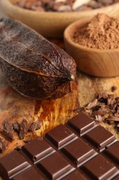 Cocoa pod, powder and chocolate on wooden table, closeup