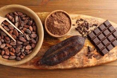 Cocoa pod, beans, powder and chocolate on wooden table, top view