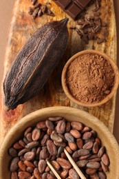 Cocoa pod, beans, powder and chocolate on brown background, top view