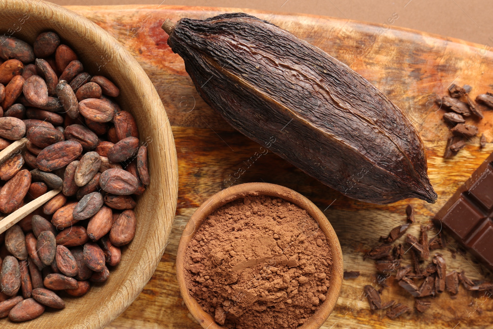 Photo of Cocoa pod, beans and powder on brown background, top view