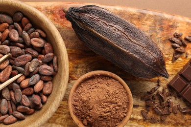 Cocoa pod, beans and powder on brown background, top view