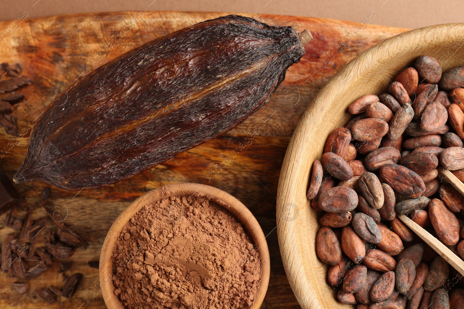 Photo of Cocoa pod, beans and powder on brown background, top view