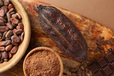 Photo of Cocoa pod, beans and powder on brown background, top view