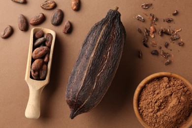 Photo of Cocoa pod, beans and powder on brown background, flat lay