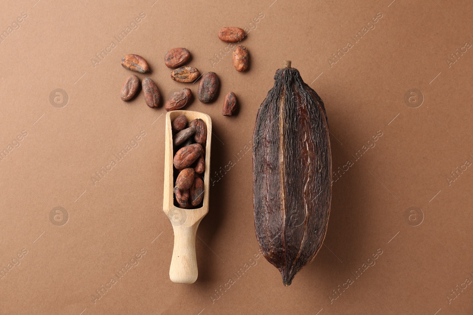 Photo of Cocoa pod and beans on brown background, flat lay