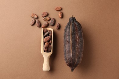 Cocoa pod and beans on brown background, flat lay