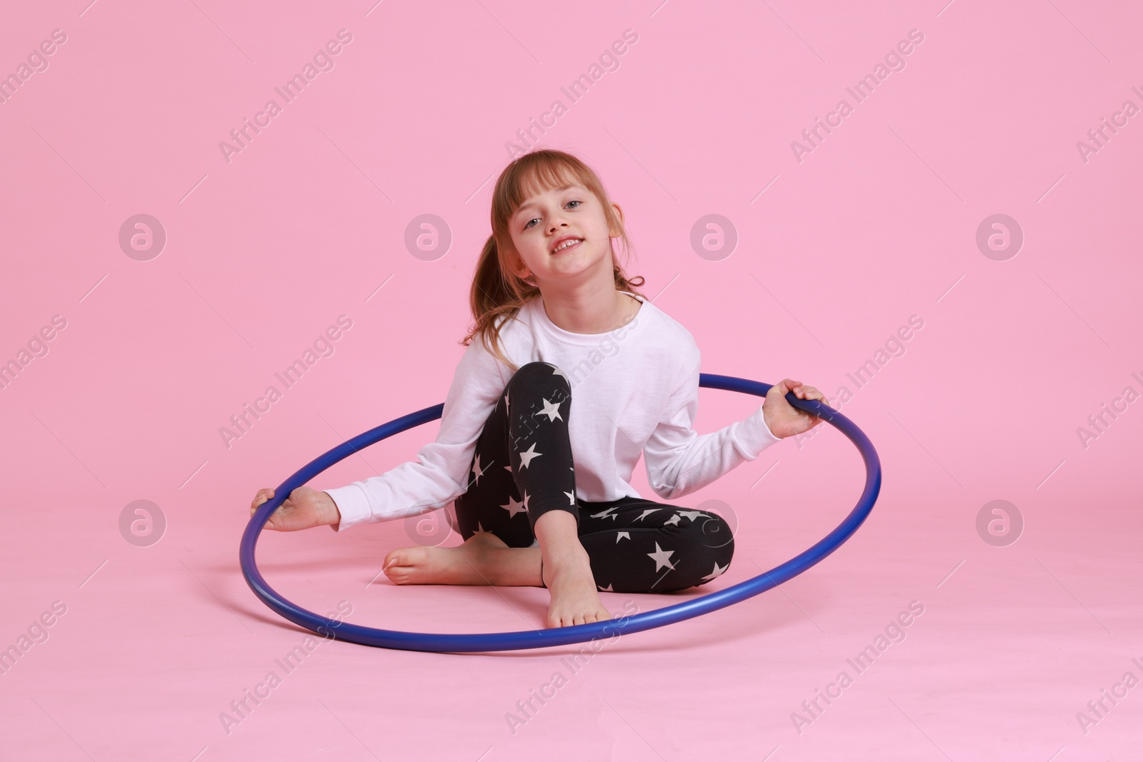 Photo of Cute little girl with hula hoop on pink background