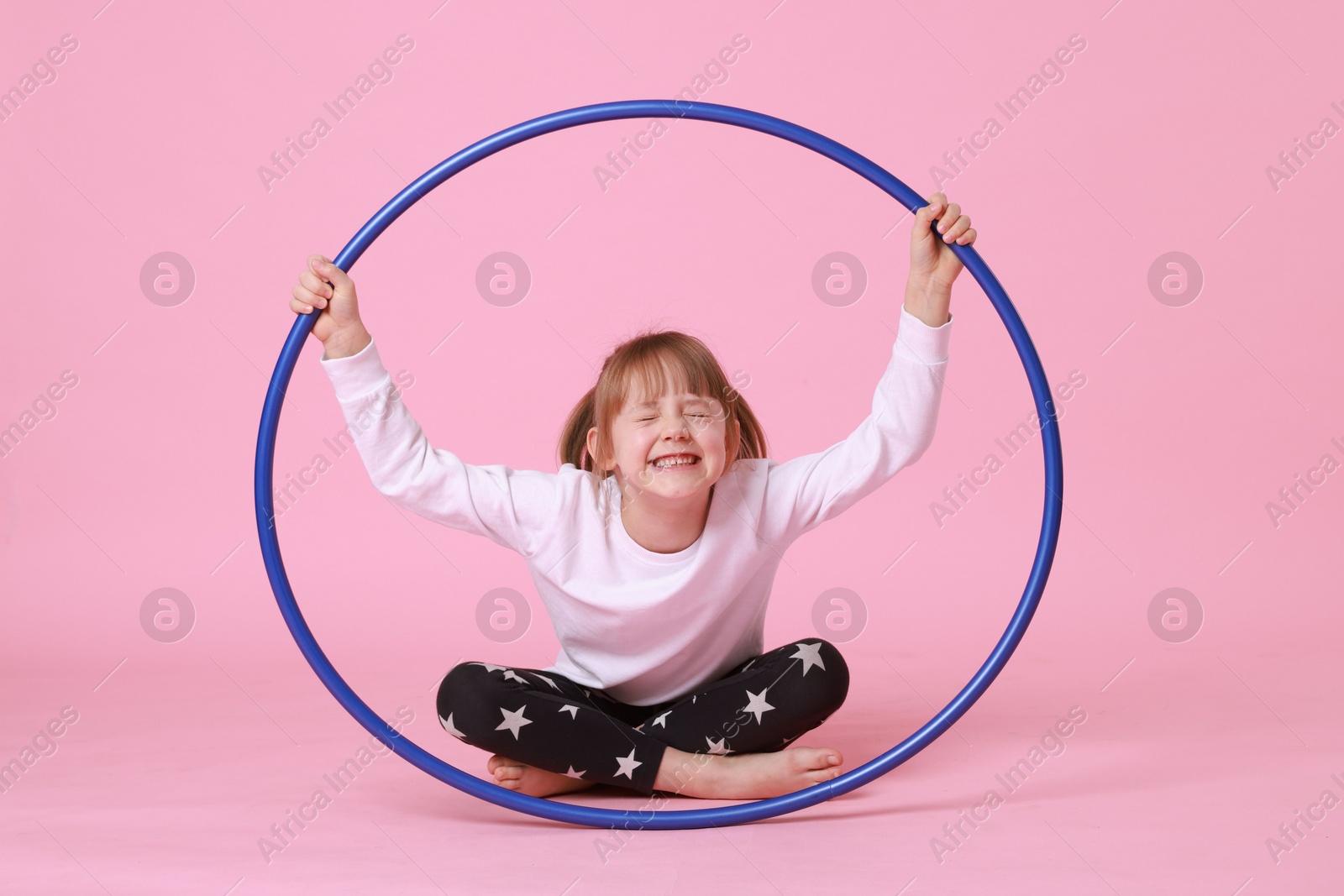 Photo of Cute little girl with hula hoop on pink background