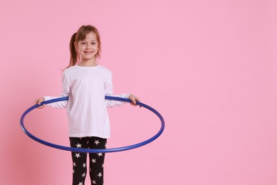 Photo of Cute little girl with hula hoop on pink background, space for text