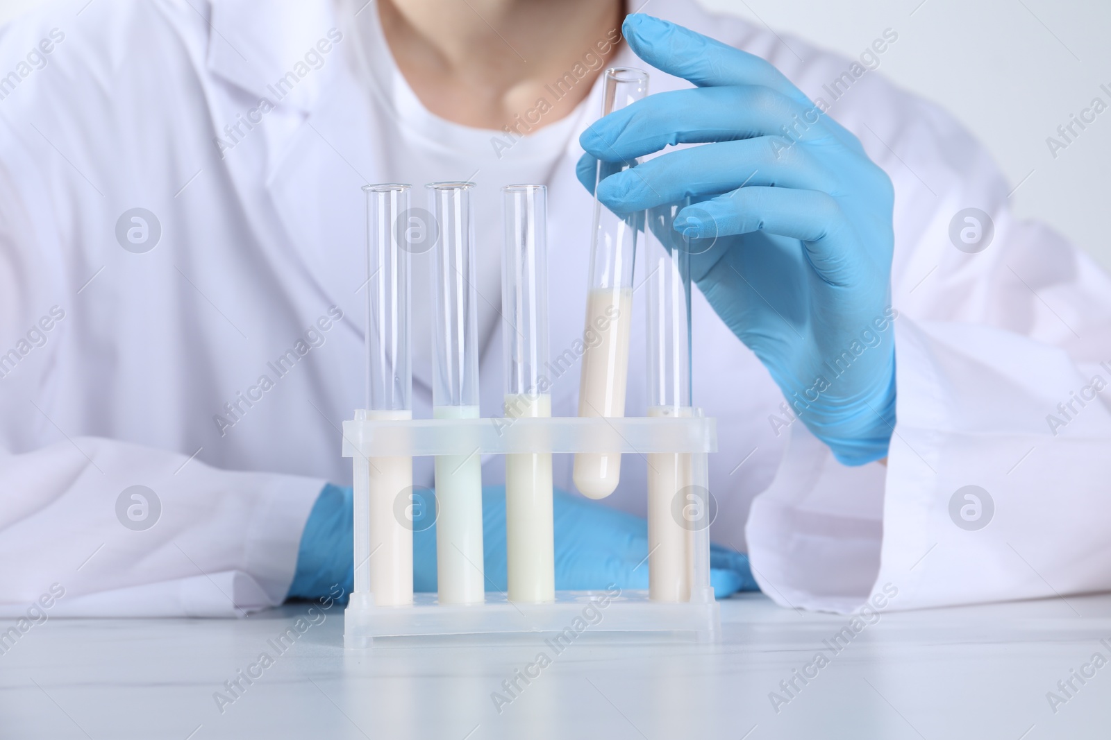 Photo of Laboratory testing. Scientist working with test tubes at white marble table, closeup