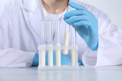 Photo of Laboratory testing. Scientist working with test tubes at white marble table, closeup