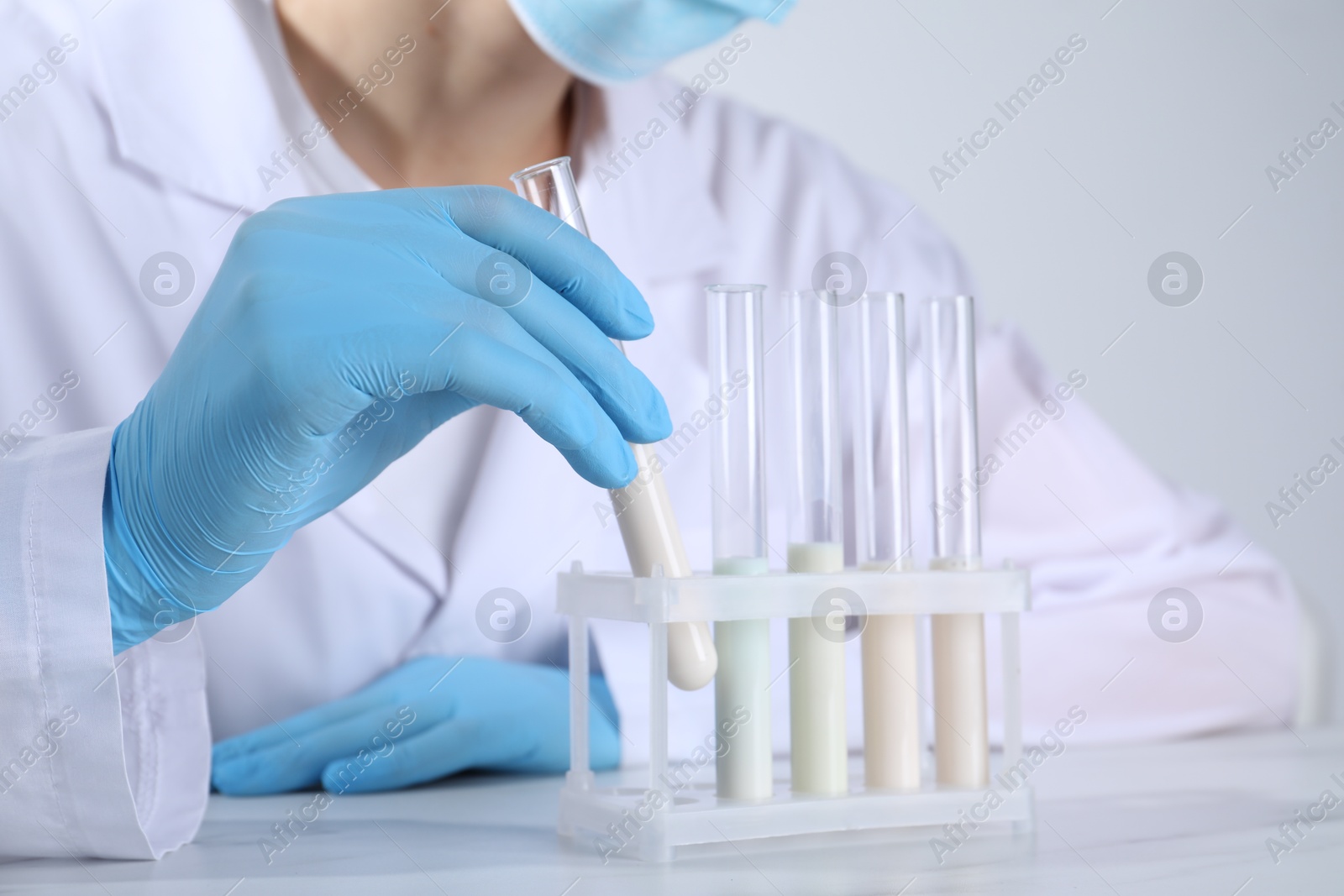 Photo of Laboratory testing. Scientist working with test tubes at white marble table, closeup