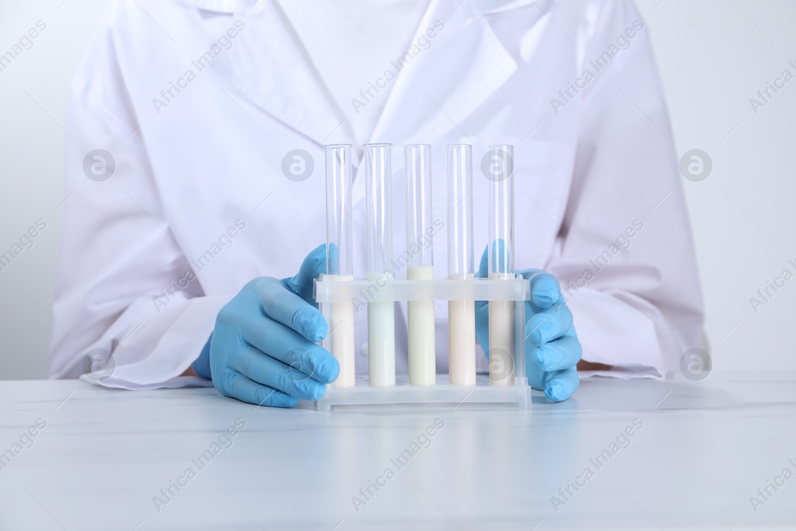 Photo of Laboratory testing. Scientist working with test tubes at white marble table, closeup