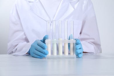 Photo of Laboratory testing. Scientist working with test tubes at white marble table, closeup