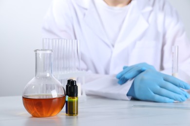 Photo of Laboratory testing. Scientist working at white marble table, focus on glassware