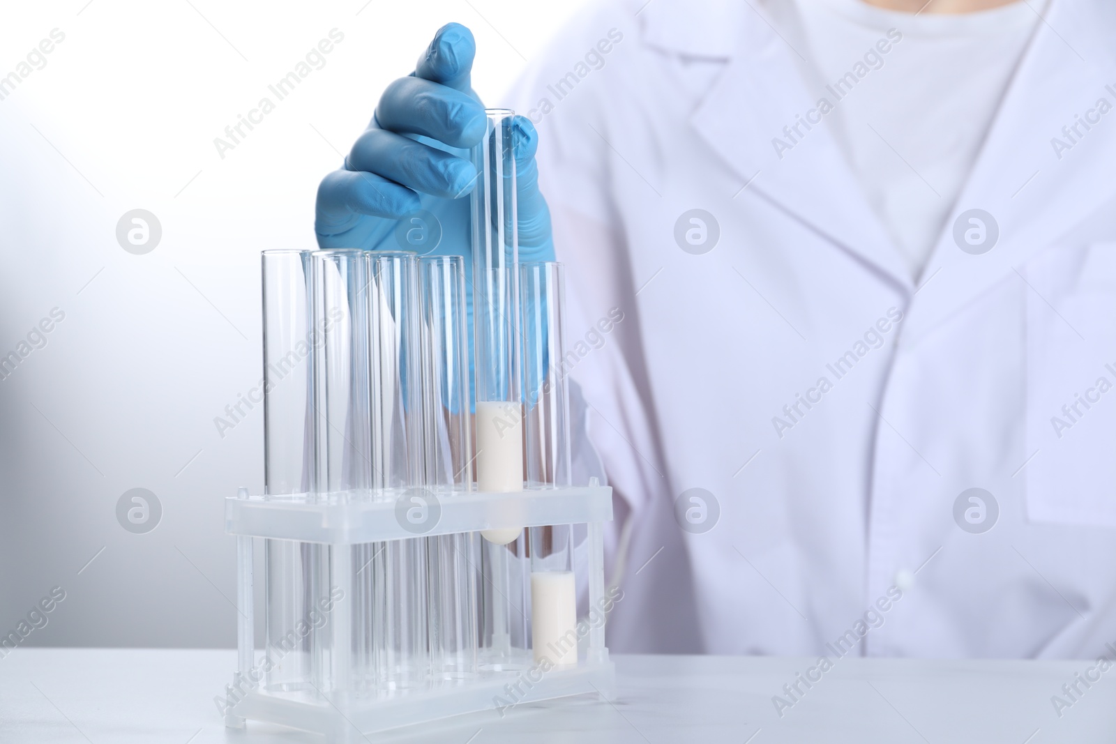 Photo of Laboratory testing. Scientist working with test tubes at white marble table, closeup