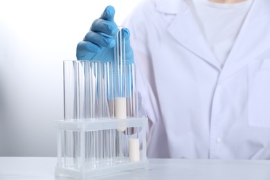 Photo of Laboratory testing. Scientist working with test tubes at white marble table, closeup