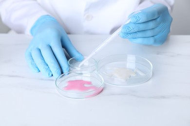 Photo of Laboratory testing. Scientist working with Petri dishes at white marble table, closeup