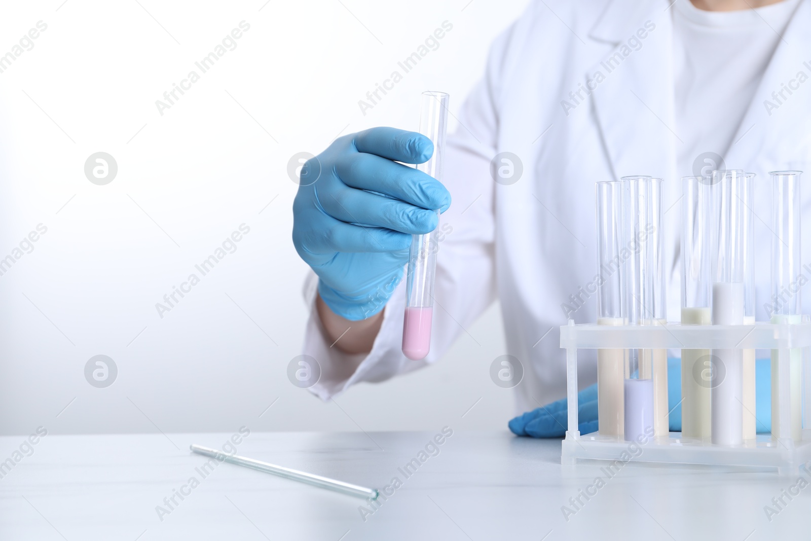 Photo of Laboratory testing. Scientist working with test tubes at white marble table, closeup