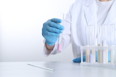 Photo of Laboratory testing. Scientist working with test tubes at white marble table, closeup