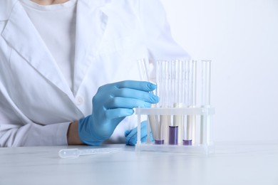 Photo of Laboratory testing. Scientist working with test tubes at white marble table, closeup