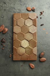 Tasty Dubai chocolate with pistachio, knafeh and cocoa beans on grey textured table, flat lay