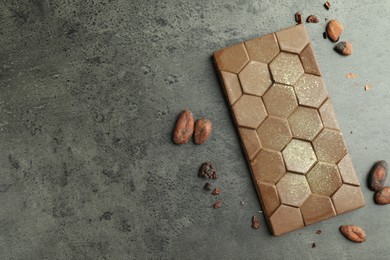 Tasty Dubai chocolate with pistachio, knafeh and cocoa beans on grey textured table, flat lay. Space for text