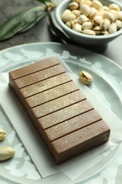 Photo of Tasty Dubai chocolate with pistachios and knafeh on grey table, closeup