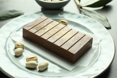 Photo of Tasty Dubai chocolate with pistachios and knafeh on grey table, closeup