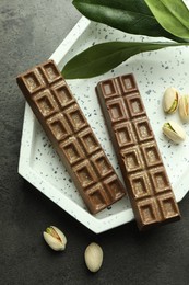 Photo of Tasty Dubai chocolate with pistachios and knafeh on grey textured table, flat lay