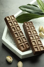 Photo of Tasty Dubai chocolate with pistachios and knafeh on grey textured table, closeup