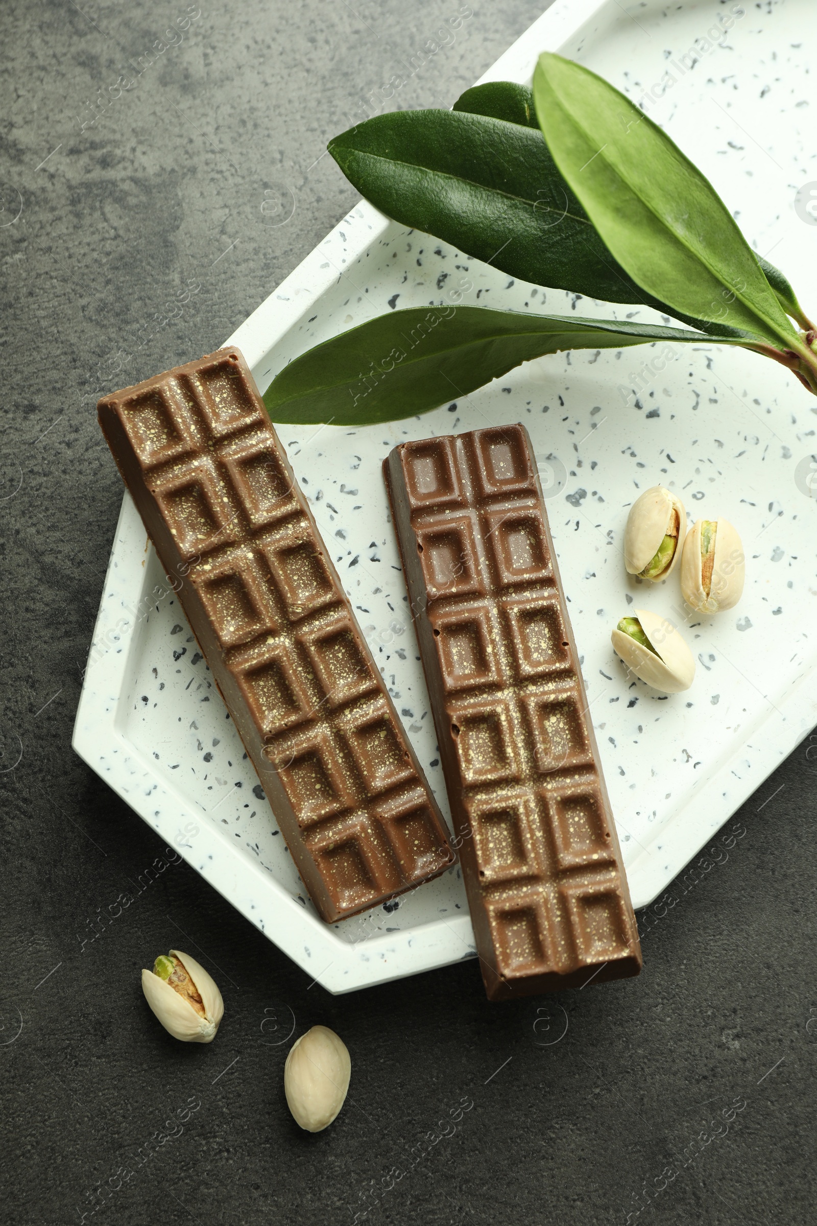 Photo of Tasty Dubai chocolate with pistachios and knafeh on grey textured table, flat lay