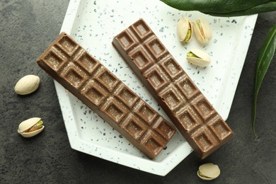 Photo of Tasty Dubai chocolate with pistachios and knafeh on grey textured table, flat lay