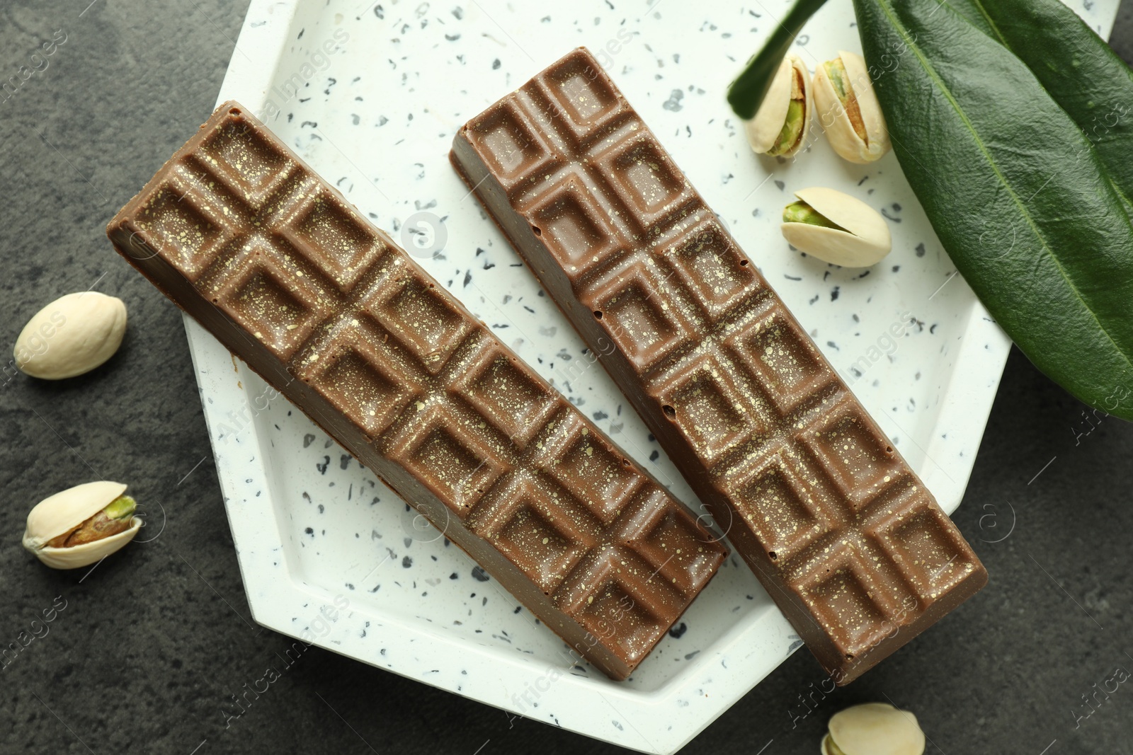 Photo of Tasty Dubai chocolate with pistachios and knafeh on grey textured table, flat lay