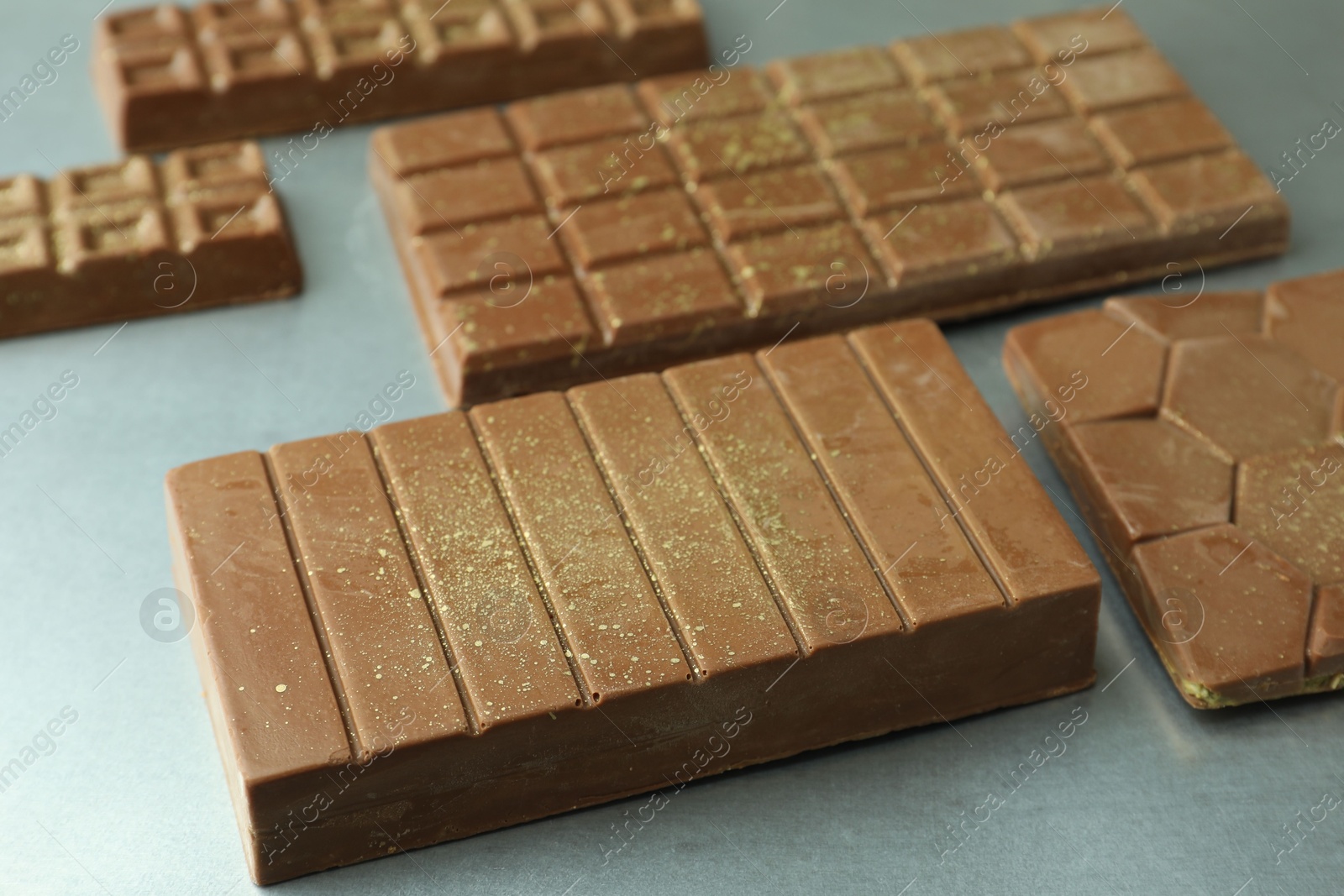 Photo of Different tasty Dubai chocolate bars with pistachios and knafeh on grey table, closeup