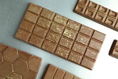 Photo of Different tasty Dubai chocolate bars with pistachios and knafeh on grey table, flat lay