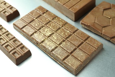 Photo of Different tasty Dubai chocolate bars with pistachios and knafeh on grey table, closeup