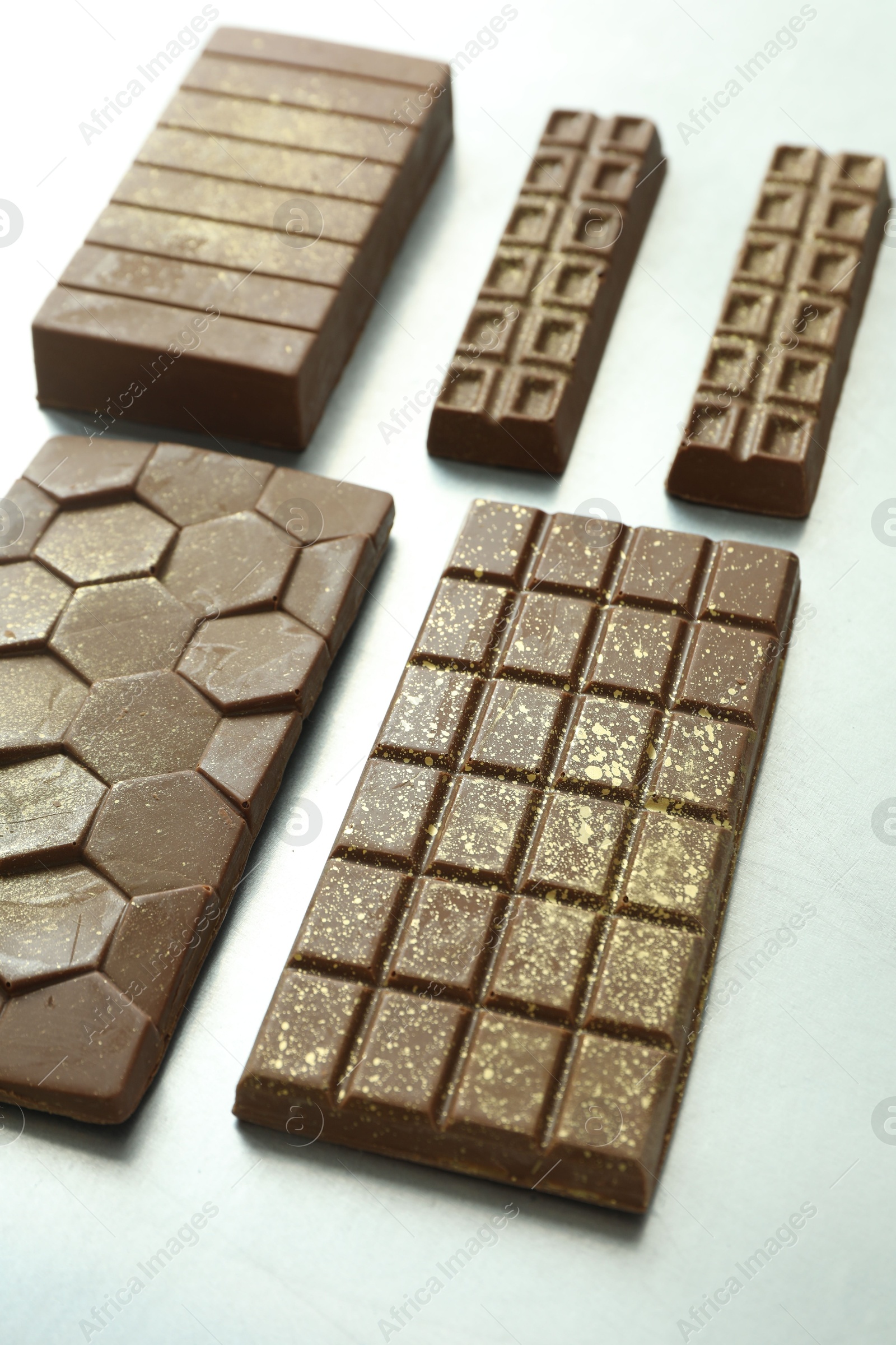 Photo of Different tasty Dubai chocolate bars with pistachios and knafeh on grey table