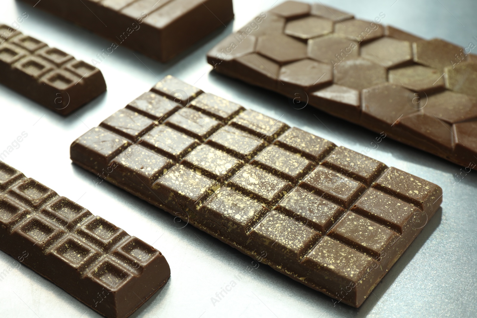 Photo of Different tasty Dubai chocolate bars with pistachios and knafeh on grey table, closeup