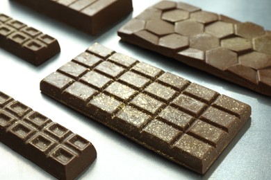 Photo of Different tasty Dubai chocolate bars with pistachios and knafeh on grey table, closeup