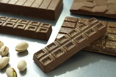 Photo of Different tasty Dubai chocolate with pistachios and knafeh on grey table, closeup