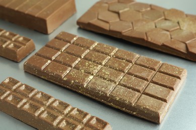 Photo of Different tasty Dubai chocolate bars with pistachios and knafeh on grey table, closeup