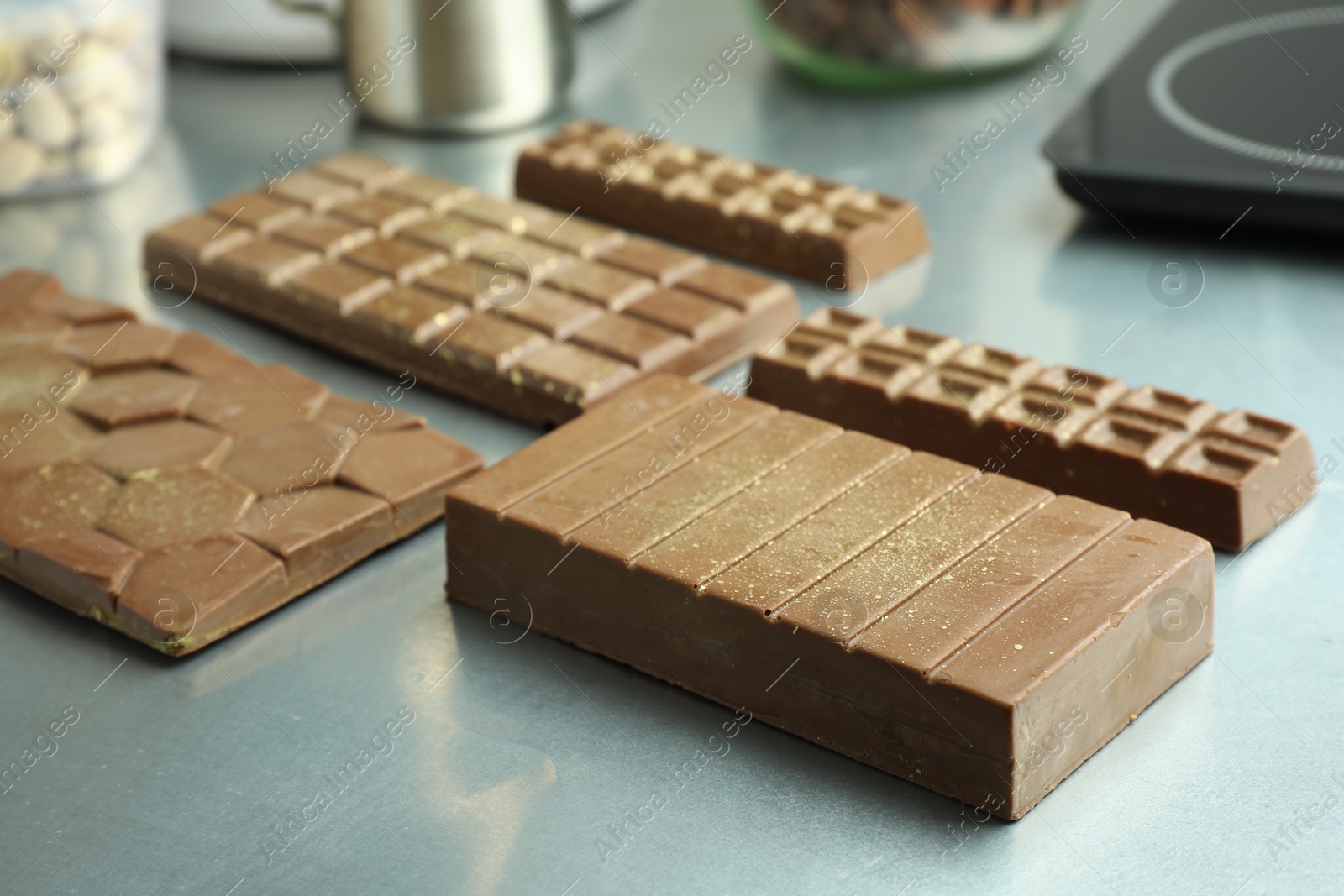 Photo of Different tasty Dubai chocolate bars with pistachios and knafeh on grey table, closeup