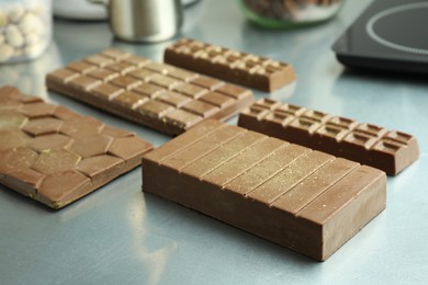 Photo of Different tasty Dubai chocolate bars with pistachios and knafeh on grey table, closeup