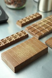 Photo of Different tasty Dubai chocolate bars with pistachios and knafeh on grey table