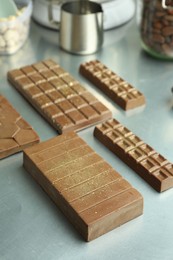 Photo of Different tasty Dubai chocolate bars with pistachios and knafeh on grey table