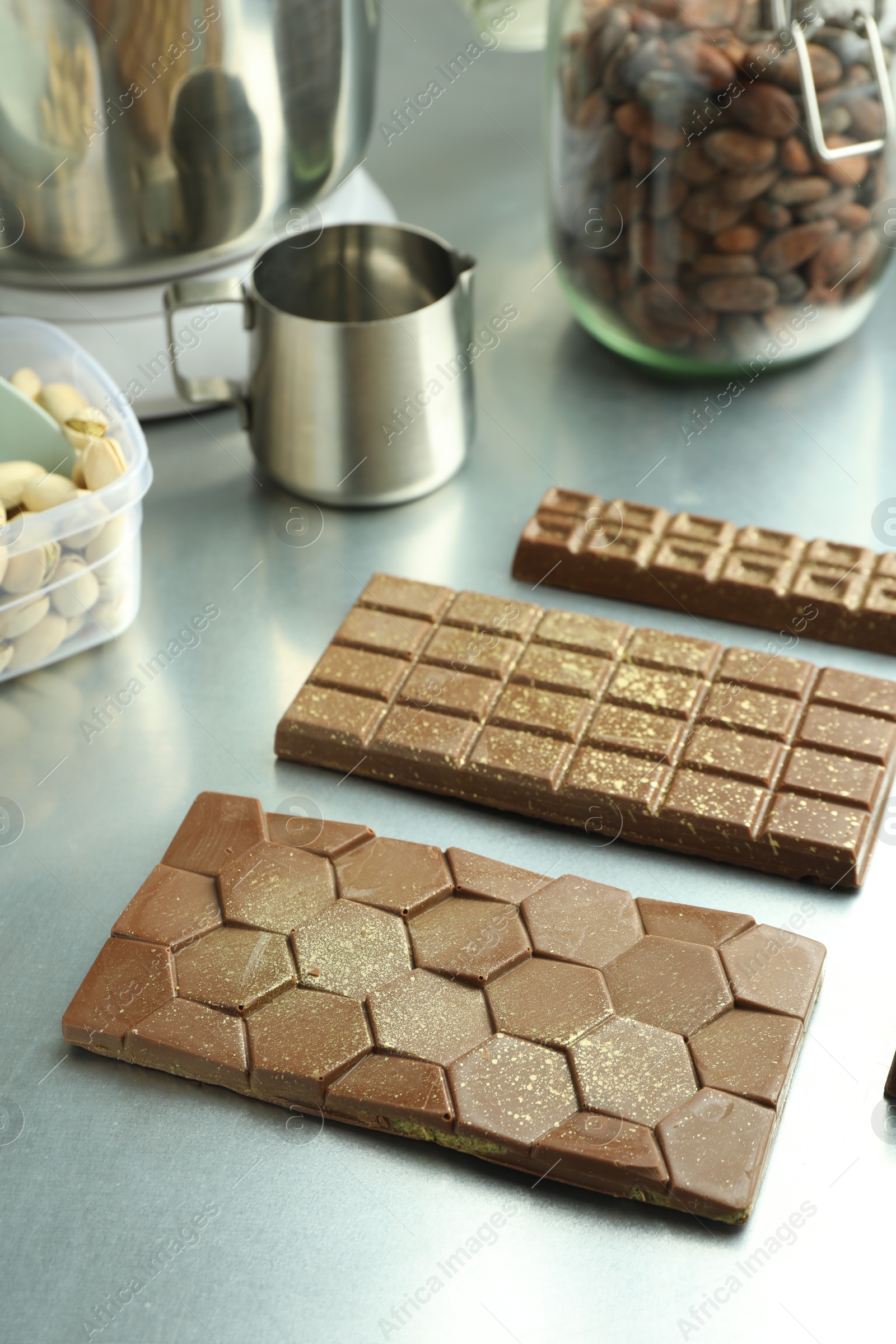 Photo of Different tasty Dubai chocolate bars with pistachios and knafeh on grey table