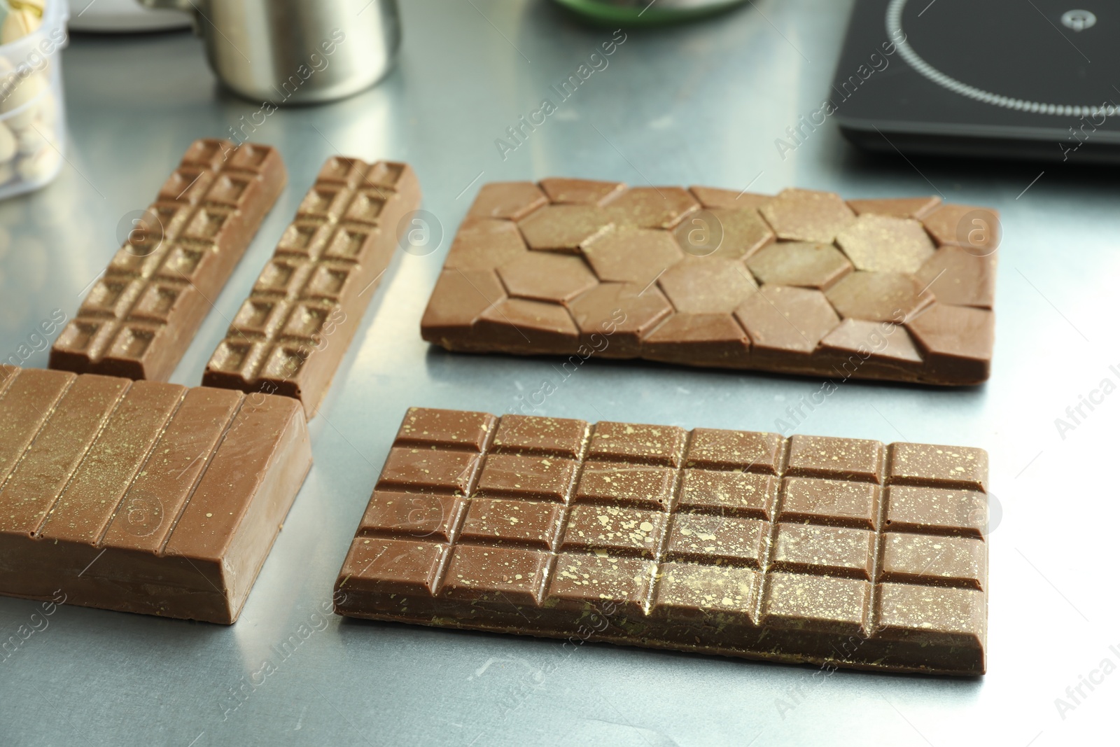 Photo of Different tasty Dubai chocolate bars with pistachios and knafeh on grey table